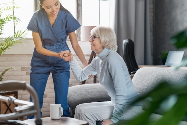 Photo professional caregiver taking care of elderly woman at home