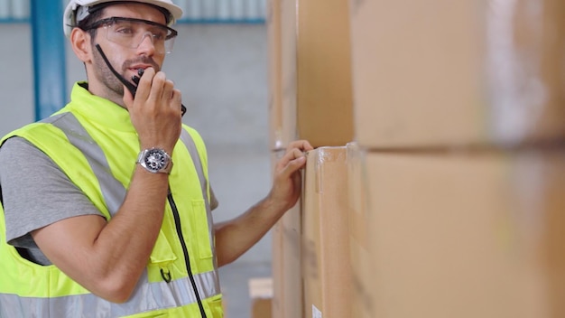 Il lavoratore professionista del carico parla alla radio portatile per contattare un altro lavoratore. concetto di comunicazione di fabbrica e magazzino.