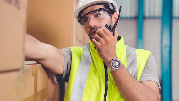 Professional cargo worker talks on portable radio to contact another worker 