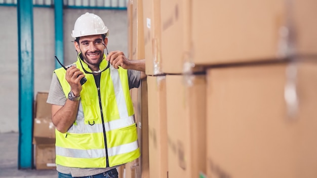 Professional cargo worker talks on portable radio to contact another worker 