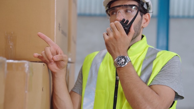 Professional cargo worker talks on portable radio to contact another worker.