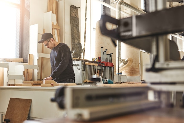 Professional carpenter at work he is carving wood using a woodworking tool