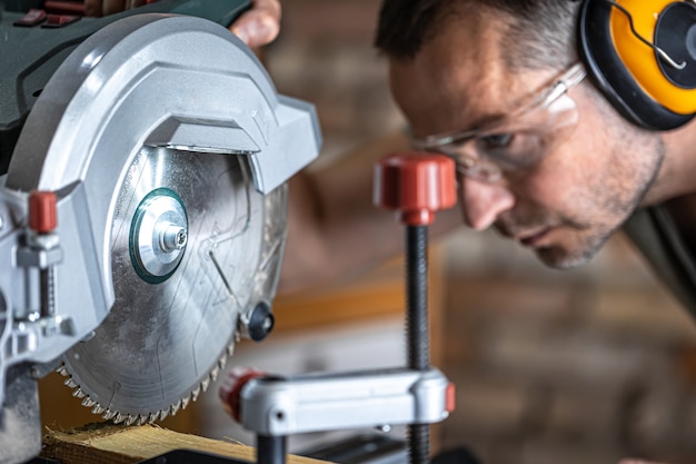 A professional carpenter works with a circular saw miter saw in a workshop.