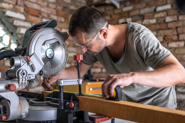 A professional carpenter works with a circular saw miter saw in a workshop.