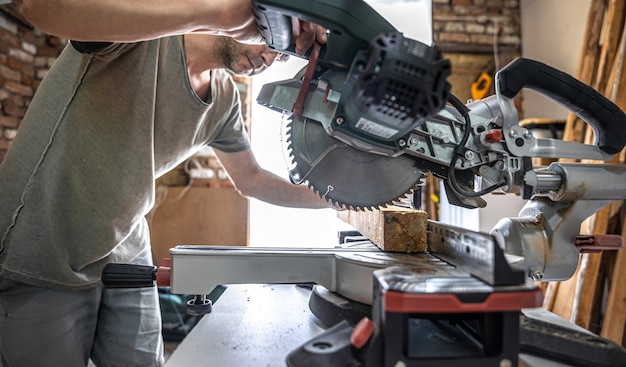 A professional carpenter works with a circular saw miter saw in a workshop.