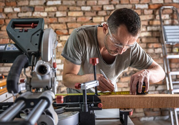 A professional carpenter works with a circular saw miter saw in a workshop.