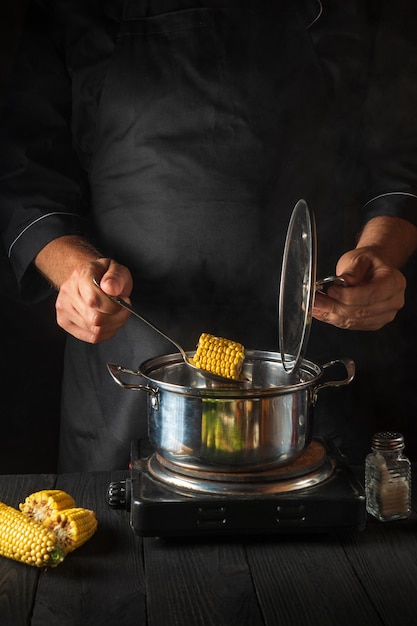 Профессиональный шеф-повар готовит кукурузу Крупный план повара - рука во время приготовления пищи на кухне ресторана