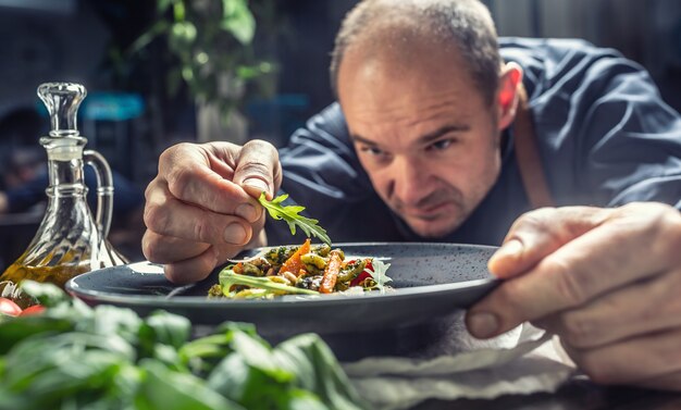 A professional chef decorates a meal just before serving it to a customer in a restaurant pub or hotel.