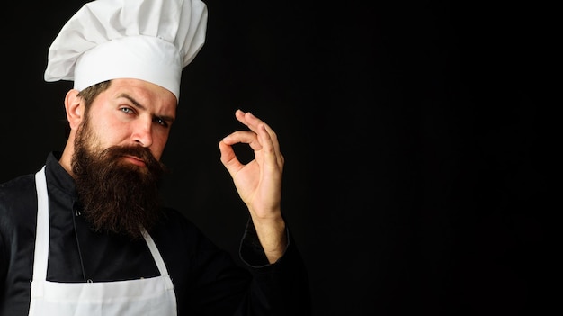Профессиональный шеф-повар в униформе показывает знак вкусного повара или пекаря жестом одобрения вкуса
