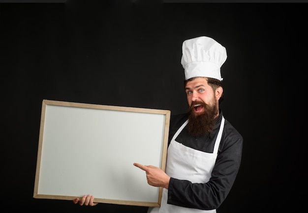 Professional chef on kitchen empty menu chalkboard with copy space for text master chef baker or