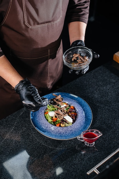 Photo a professional chef prepares a delicious fresh salad of green vegetables and juicy veal in a modern and stylish restaurant