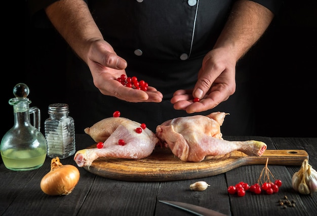 Professional chef prepares raw chicken legs in the restaurant kitchen