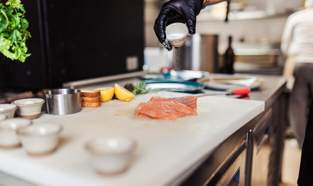 Professional chef in restaurant kitchen preparing delicious meal with meat and vegetables.