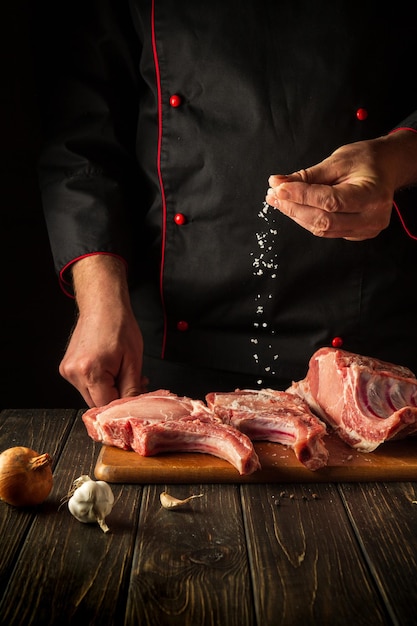 Professional chef sprinkles raw ribs with salt The concept of cooking delicious food for the hotel