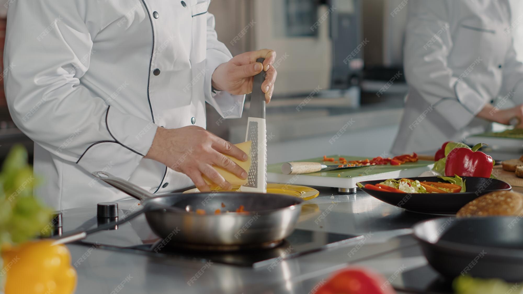 Premium Photo | Professional chef using grater to add shredded cheese