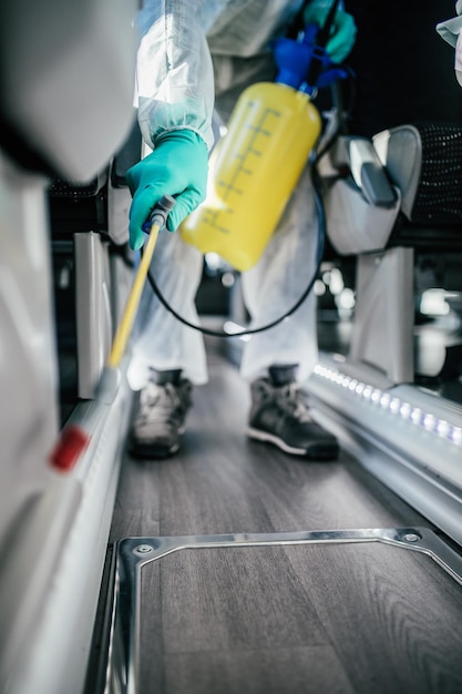 Professional chemical cleaning of bus seats. Bus disinfection. Exterminator in workwear.