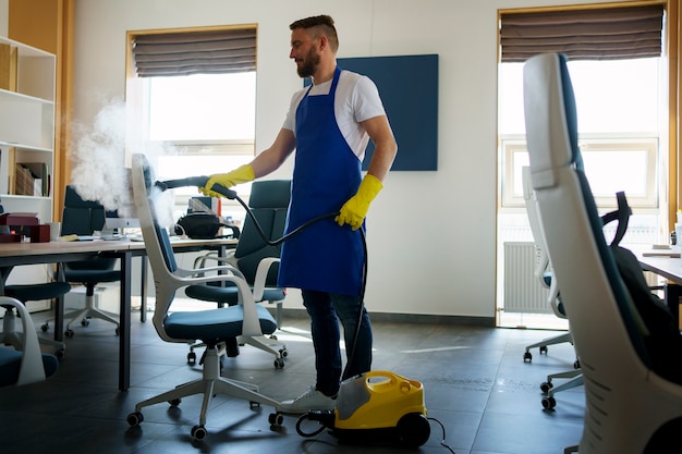 Foto addetto al servizio di pulizia professionale che utilizza un pulitore a vapore in ufficio