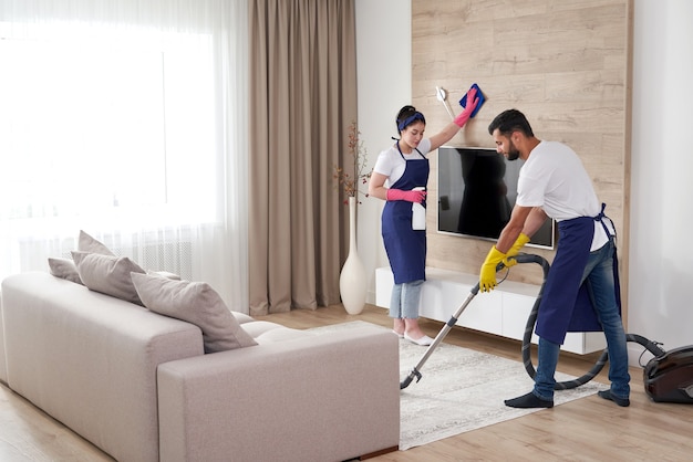 Professional cleaning service team cleans living room in modern apartment