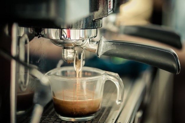 Professional coffee machine preparing cup of coffee.