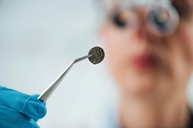 Professional coin expert examining ancient coins with magnifying glass