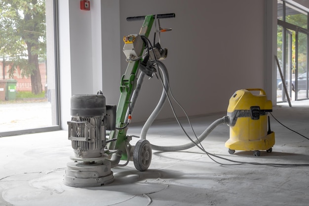 Professional concrete floor grinder vacuum cleaner connected to\
the grinder industrial concrete floor grinding