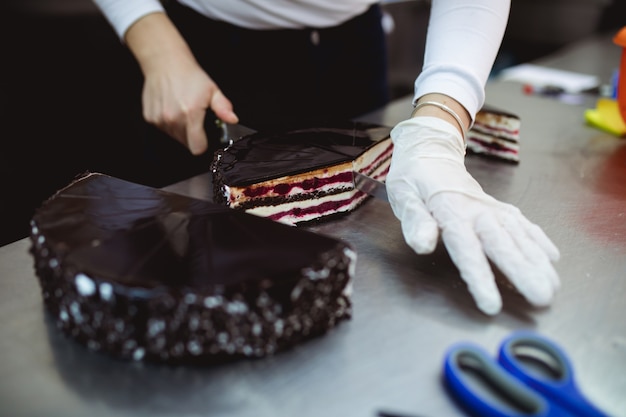 A professional confectioner cutting cake.