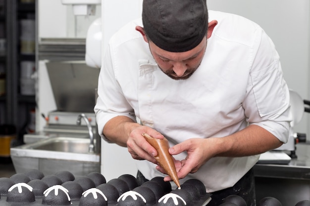 Professional confectioner making chocolate sweets at confectionery shop.