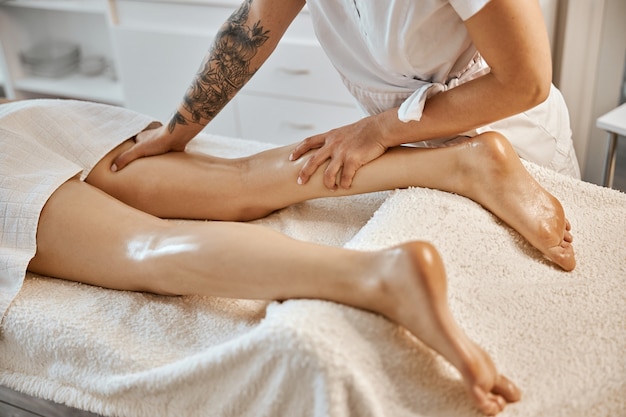 Professional confident massage master is doing procedures to caucasian woman in minimalistic modern