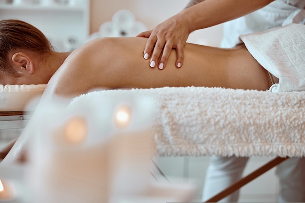 Professional confident massage master is doing procedures to caucasian woman in minimalistic modern