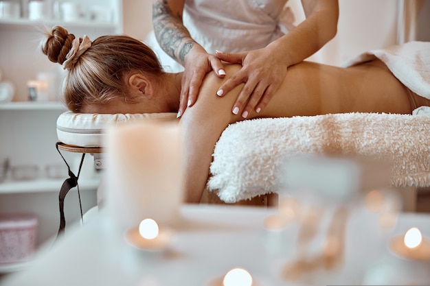 Professional confident massage master is doing procedures to caucasian woman in minimalistic modern