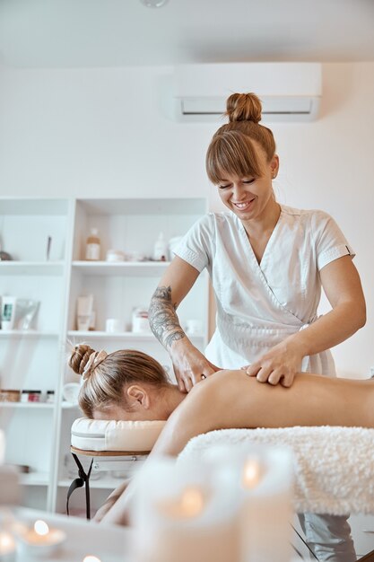 Professional confident massage master is doing procedures to caucasian woman in minimalistic modern