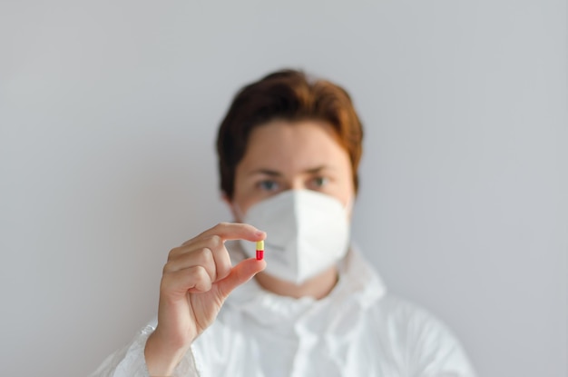 professional confident young doctor in medical mask, white coat. glass bottle, vaccination COVID 19