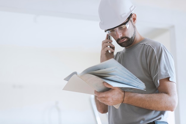 Professional construction worker checking a project and calling