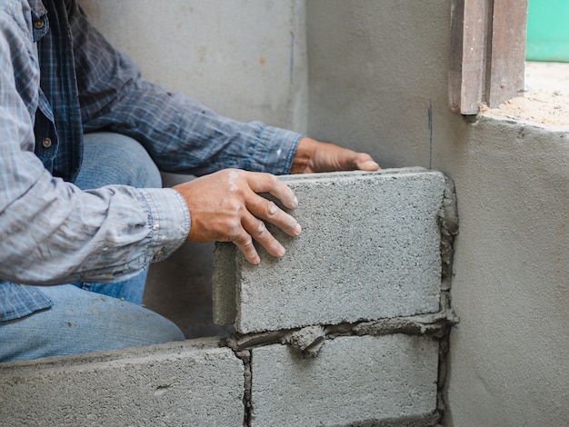 Professional construction worker laying bricks with cement.