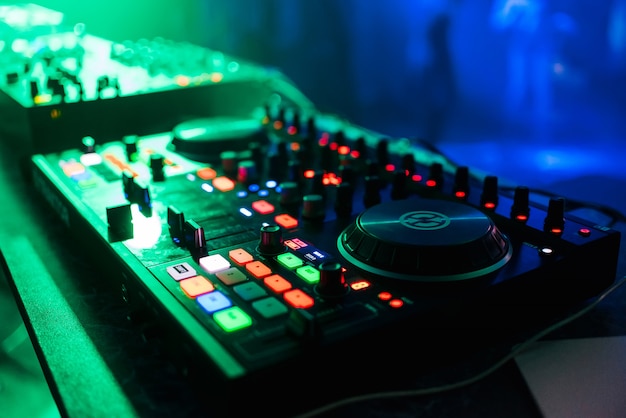 Профессиональная панель управления и микширование музыки под зелеными огнями в ночном клубе на вечеринке