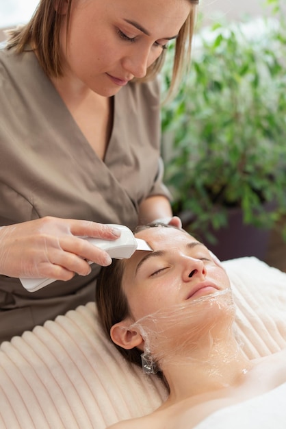 여성 고객에게 초음파 피부 청소를 하는 전문 미용사