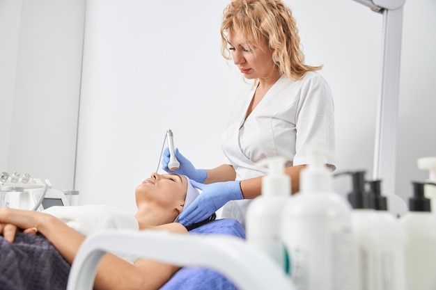 Professional cosmetologist is doing procedures for client in cabinet