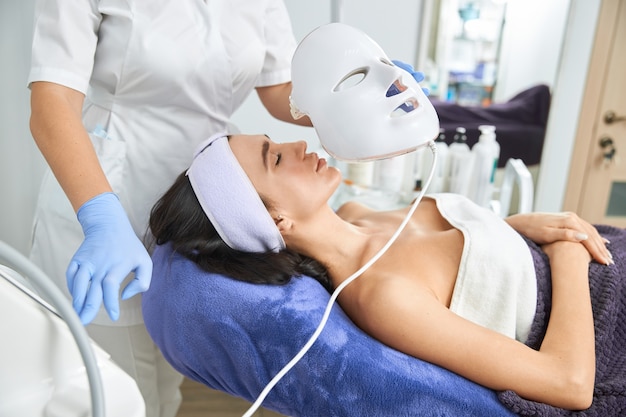 Professional cosmetologist is doing procedures for client in cabinet