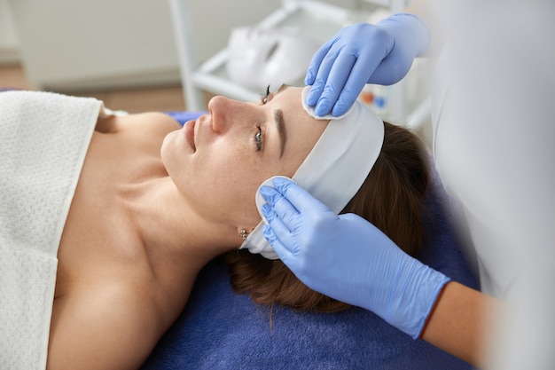 Professional cosmetologist is doing procedures for client in cabinet