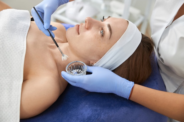 Professional cosmetologist is doing procedures for client in cabinet