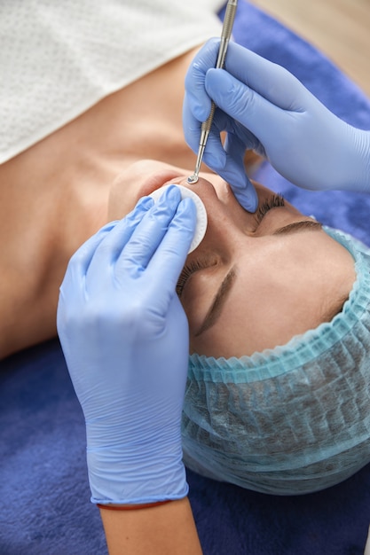 Professional cosmetologist is doing procedures for client in cabinet