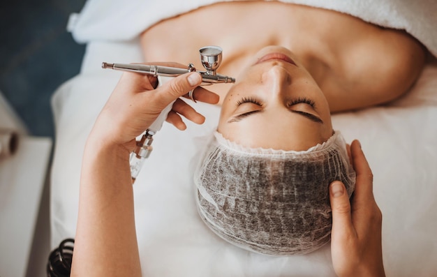 Professional cosmetologists hands doing gasliquid peeling procedure of the clients face facial treat