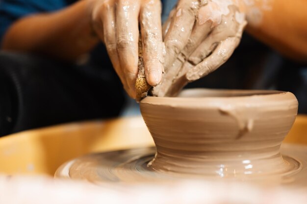 professional craftsman potter making jug of clay on potter wheel circle in workshop