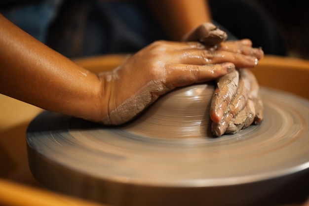 Professional craftsman potter making jug of clay on potter wheel circle in workshop