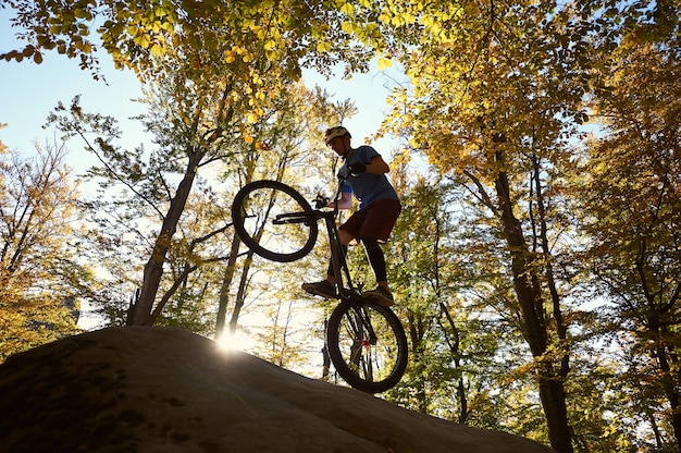 Professional cyclist balancing on trial bicycle at sunset