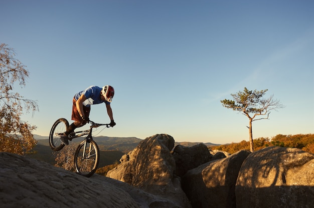 Professional cyclist balancing on trial bicycle at sunset