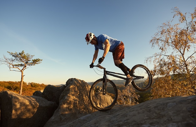 Professional cyclist balancing on trial bicycle at sunset