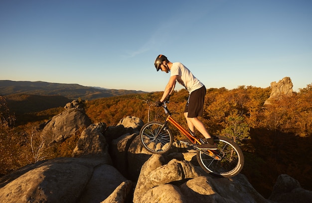 Professional cyclist balancing on trial bicycle at sunset