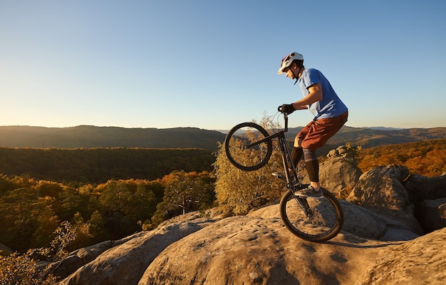 Professional cyclist balancing on trial bicycle at sunset