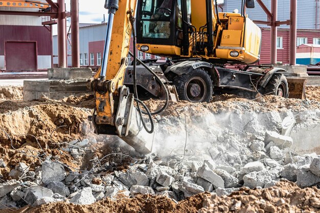 Professional demolition of reinforced concrete structures using industrial hydraulic hammer with excavator. Rods of metal fittings. Wreckage and crumbles of concrete.